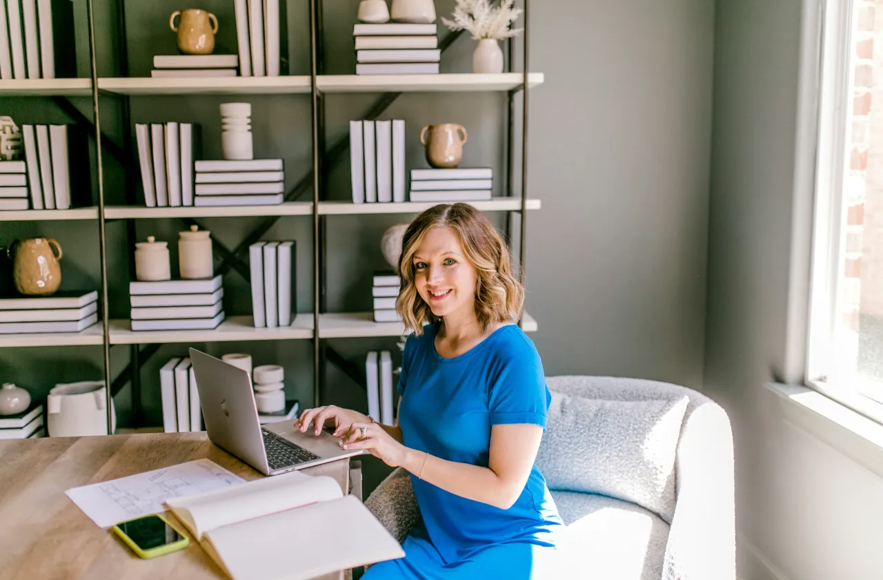 Marketer smiling at the camera while working on a laptop at her desk